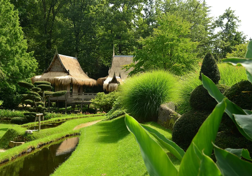 Pavillons mit Reetdach an einem Wasserlauf im östlichen Wassergarten der Schlossgärten Arcen